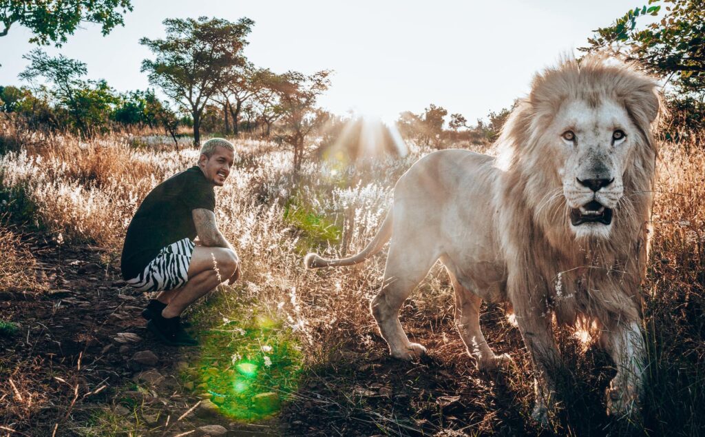 Dean is sitting in the grass locking at his lion Snow which is running towards the camera.